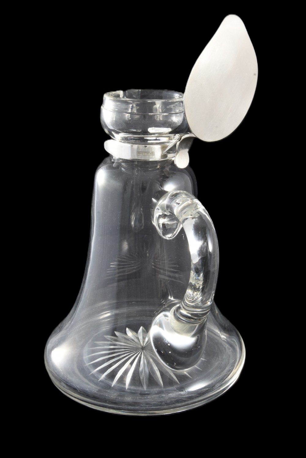 An Edwardian clear glass whisky noggin featuring a starburst cut base, applied glass loop handle, and a hallmarked sterling silver collar with a hinged lid. View IV