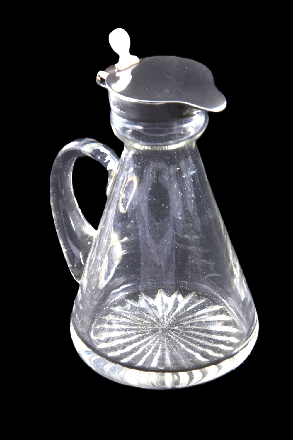 A conical clear glass whisky noggin featuring a starburst cut base, a curved glass handle, and a silver collar with a hinged lid.
