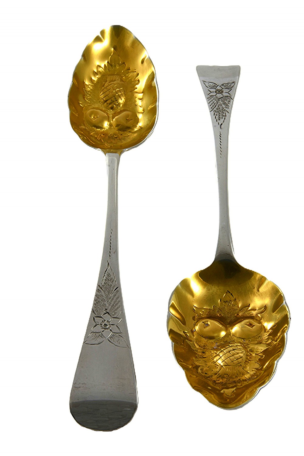 A pair of 1810 Georgian sterling silver berry spoons featuring engraved handles and gilded, repousse bowls embossed with fruit designs.