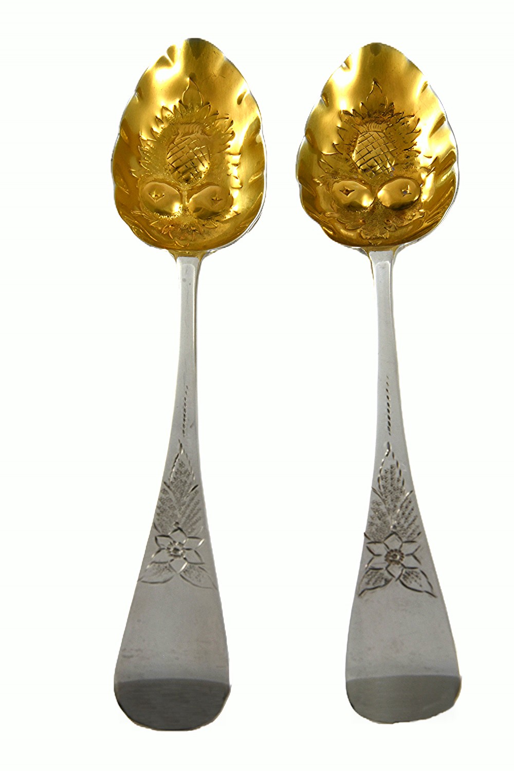 A pair of 1810 Georgian sterling silver berry spoons featuring engraved handles and gilded, repousse bowls embossed with fruit designs. View II