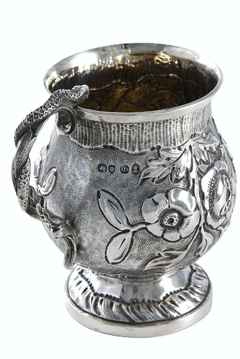 A George IV sterling silver christening mug with floral repousse work, a plain cartouche, and a curved handle set on a stepped base. View II