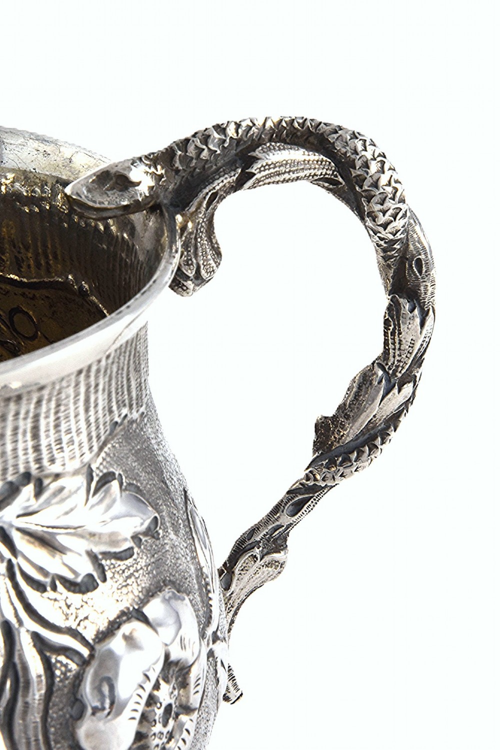 A George IV sterling silver christening mug with floral repousse work, a plain cartouche, and a curved handle set on a stepped base. View V