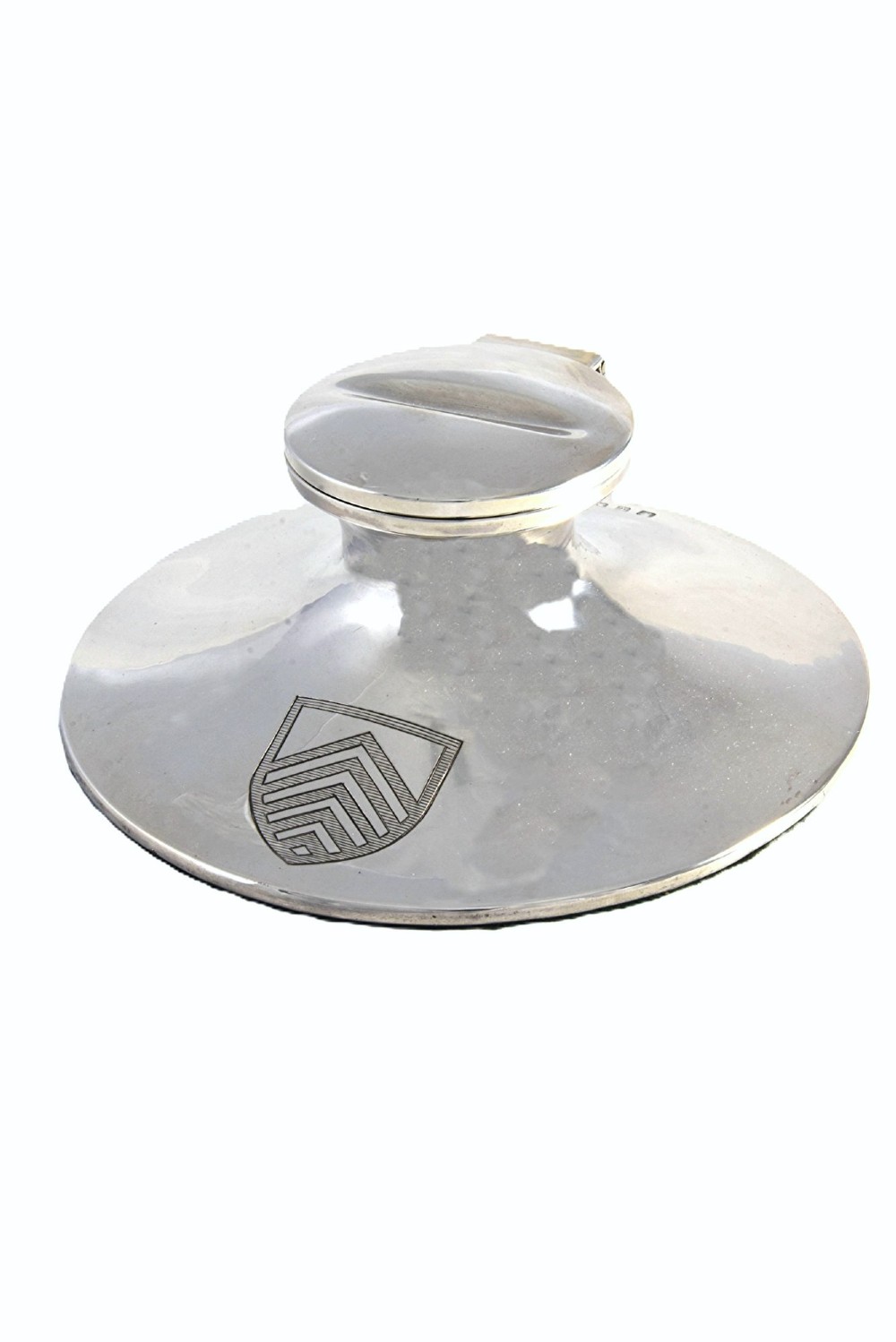A polished sterling silver capstan-shaped inkwell featuring a wide sloped base and an engraved crest motif.