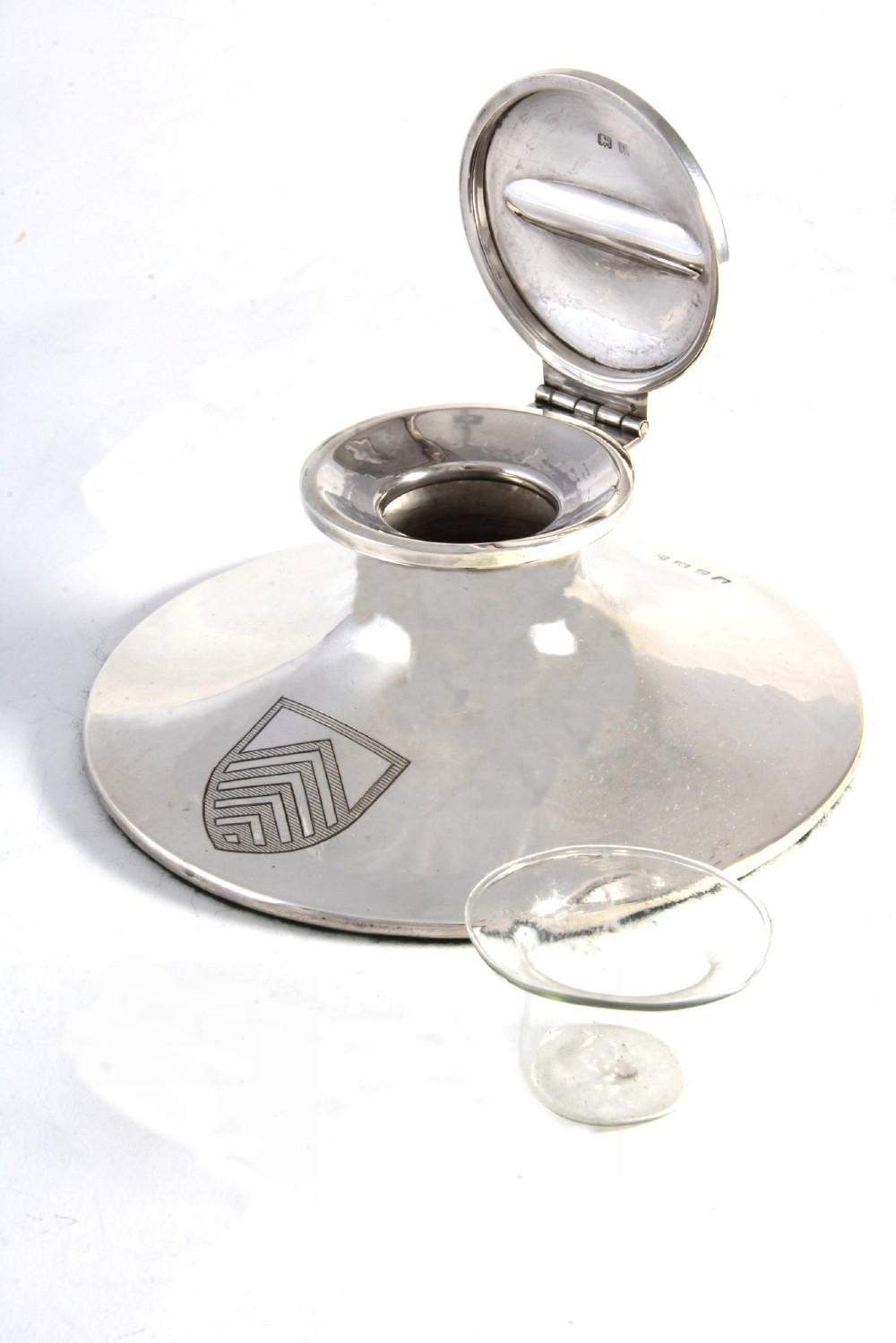 A polished sterling silver capstan-shaped inkwell featuring a wide sloped base and an engraved crest motif. View IV