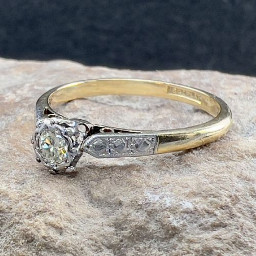 fig 1. An Art Deco 18ct yellow gold and platinum solitaire ring set with a single round diamond and decorative engraved shoulders.