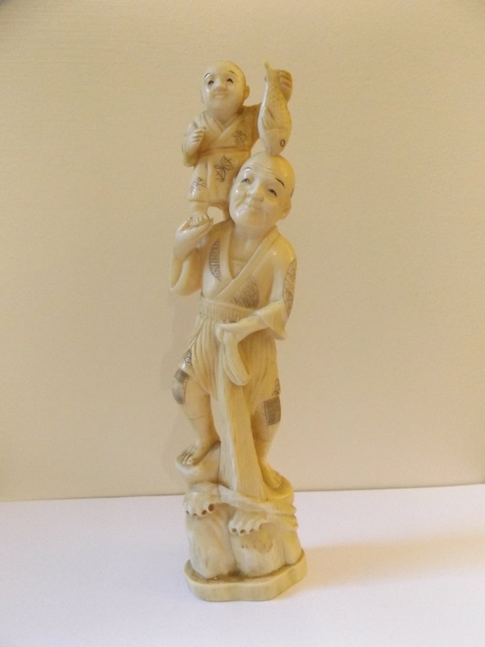 A Intricately Carved Japanese Ivory Okimono of a Fisherman Holding a Boy on his Shoulders c1890 Meiji Period 21cm High