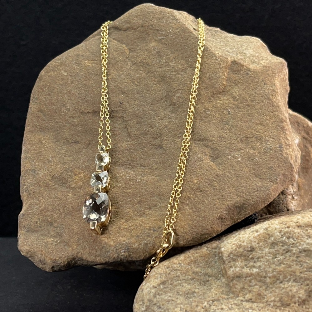 A 9ct yellow gold drop pendant featuring three graduated cushion-cut gemstones on a fine link chain. View V