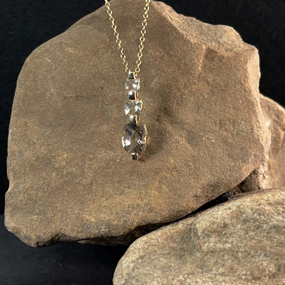 A 9ct yellow gold drop pendant featuring three graduated cushion-cut gemstones on a fine link chain. View VII