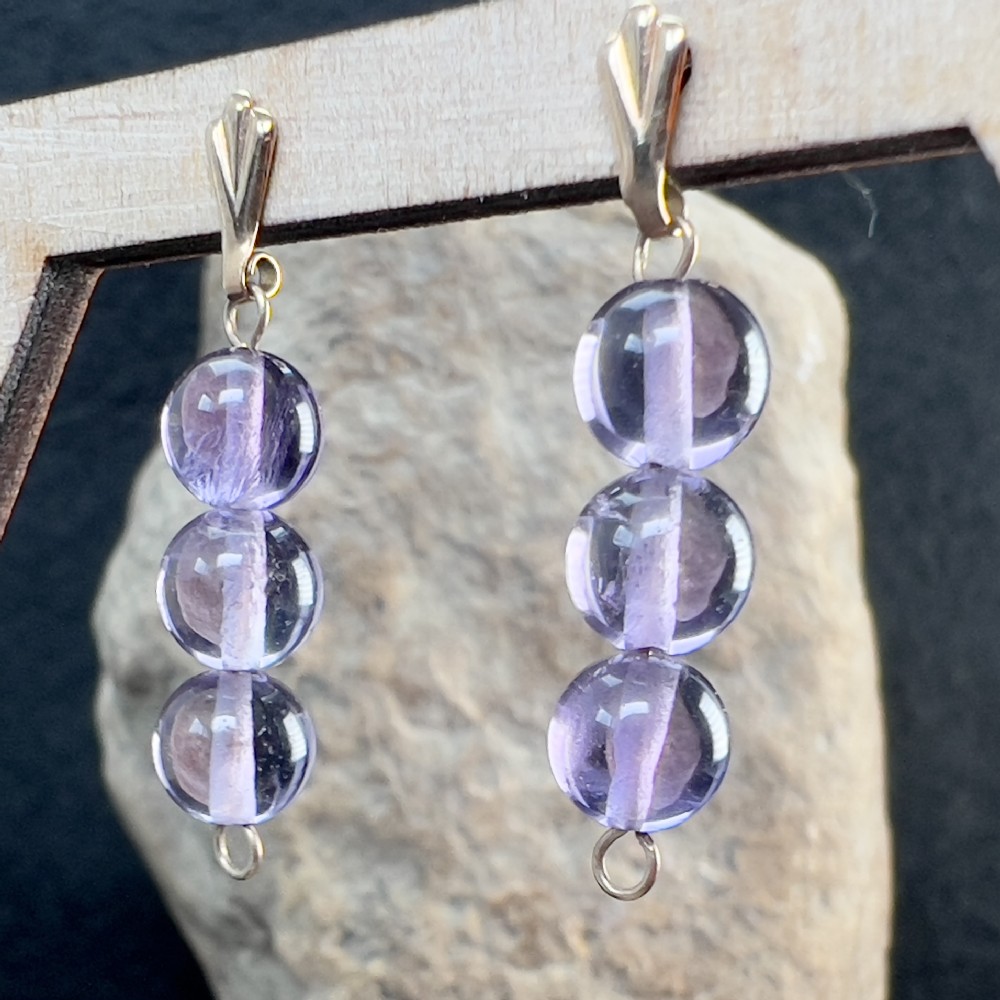 A pair of 9ct gold drop earrings featuring three polished spherical purple amethyst beads suspended vertically from gold bails.