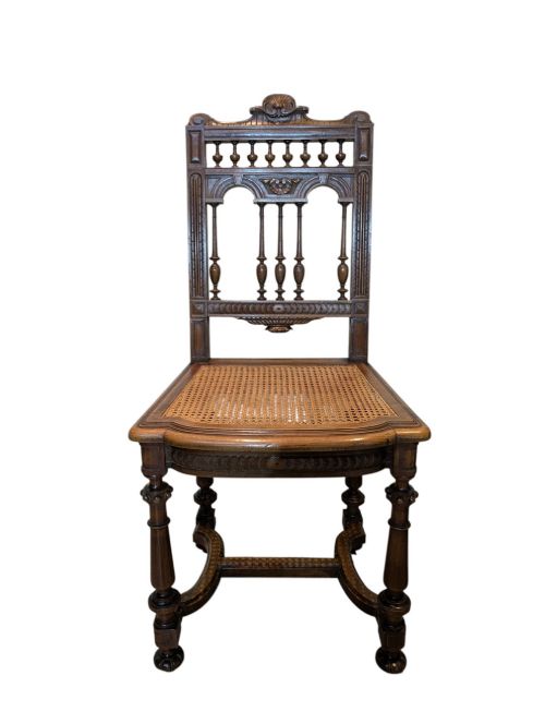 fig 1. A set of four antique dark carved oak dining chairs featuring openwork spindle backs and woven cane seats.