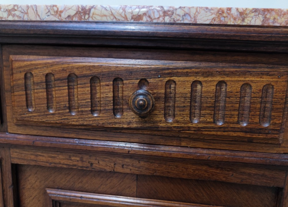 A pair of dark wood French bedside cabinets featuring carved drawer fronts, single cupboards, turned fluted legs, and variegated marble tops. View IV