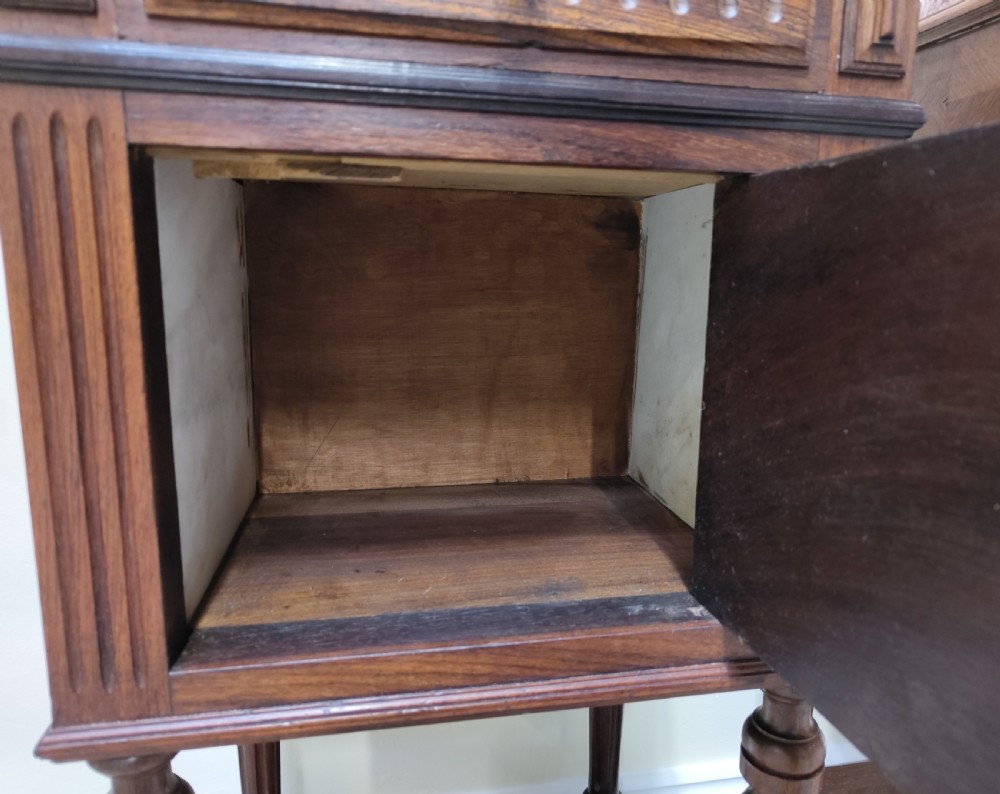 A pair of dark wood French bedside cabinets featuring carved drawer fronts, single cupboards, turned fluted legs, and variegated marble tops. View X