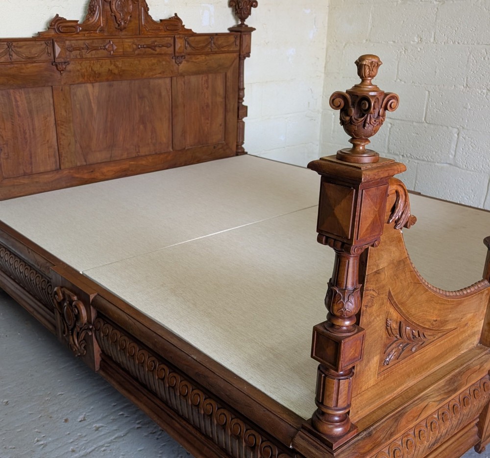 An antique king-sized wooden bed frame featuring rich burr walnut panels, crossbanded inlay, and decorative gilt bronze mounts on the headboard and footboard. View XIII