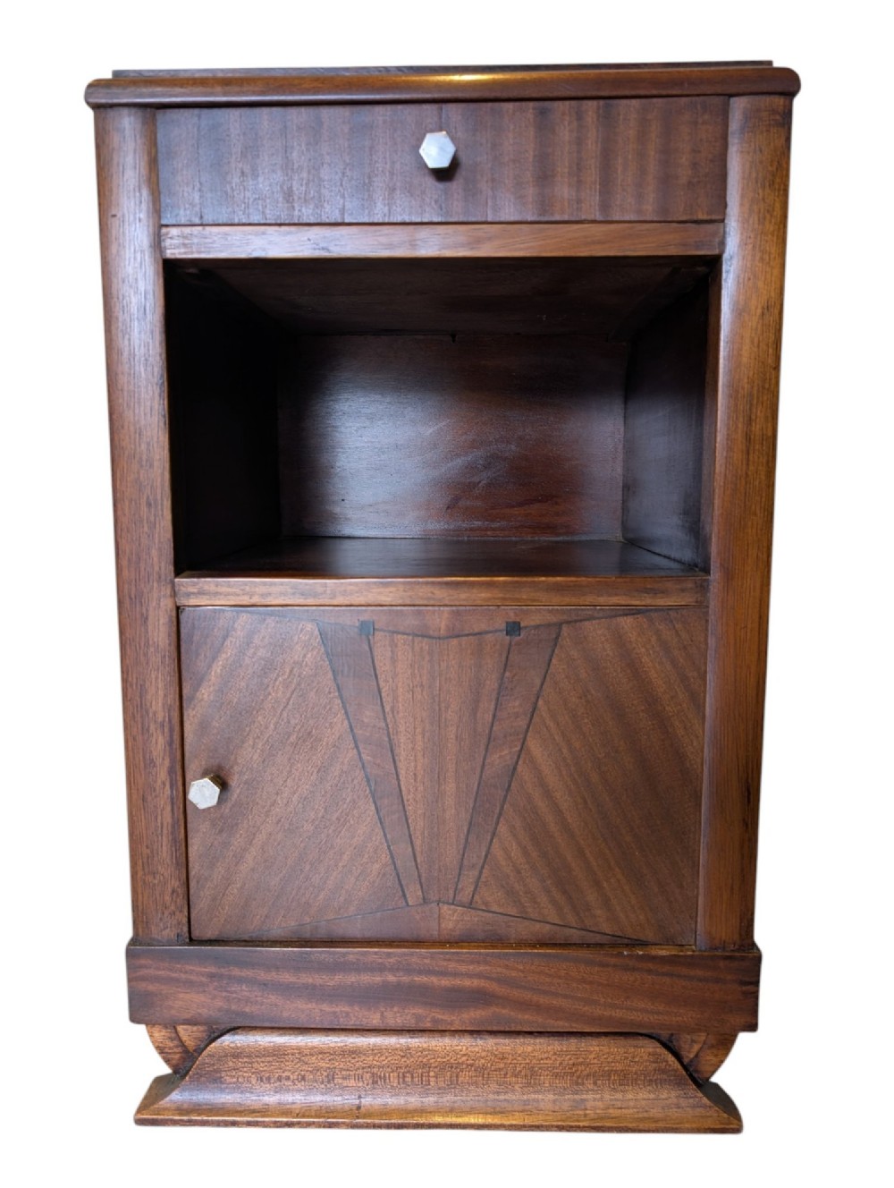 A dark brown walnut Art Deco bedside cabinet featuring a top drawer, an open central shelf, a cupboard door with geometric veneer inlay, and hexagonal metal knobs. View III