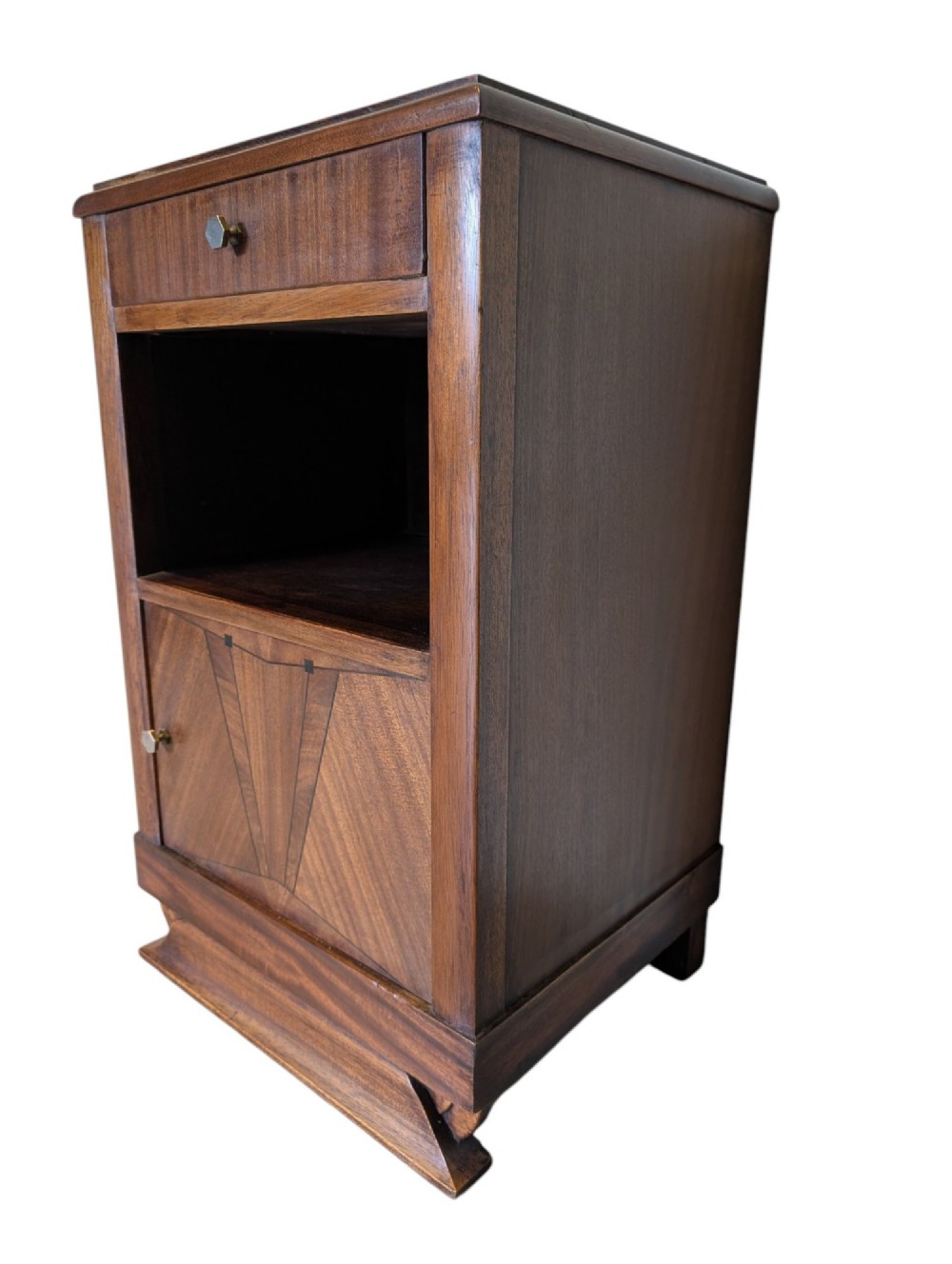 A dark brown walnut Art Deco bedside cabinet featuring a top drawer, an open central shelf, a cupboard door with geometric veneer inlay, and hexagonal metal knobs. View IV
