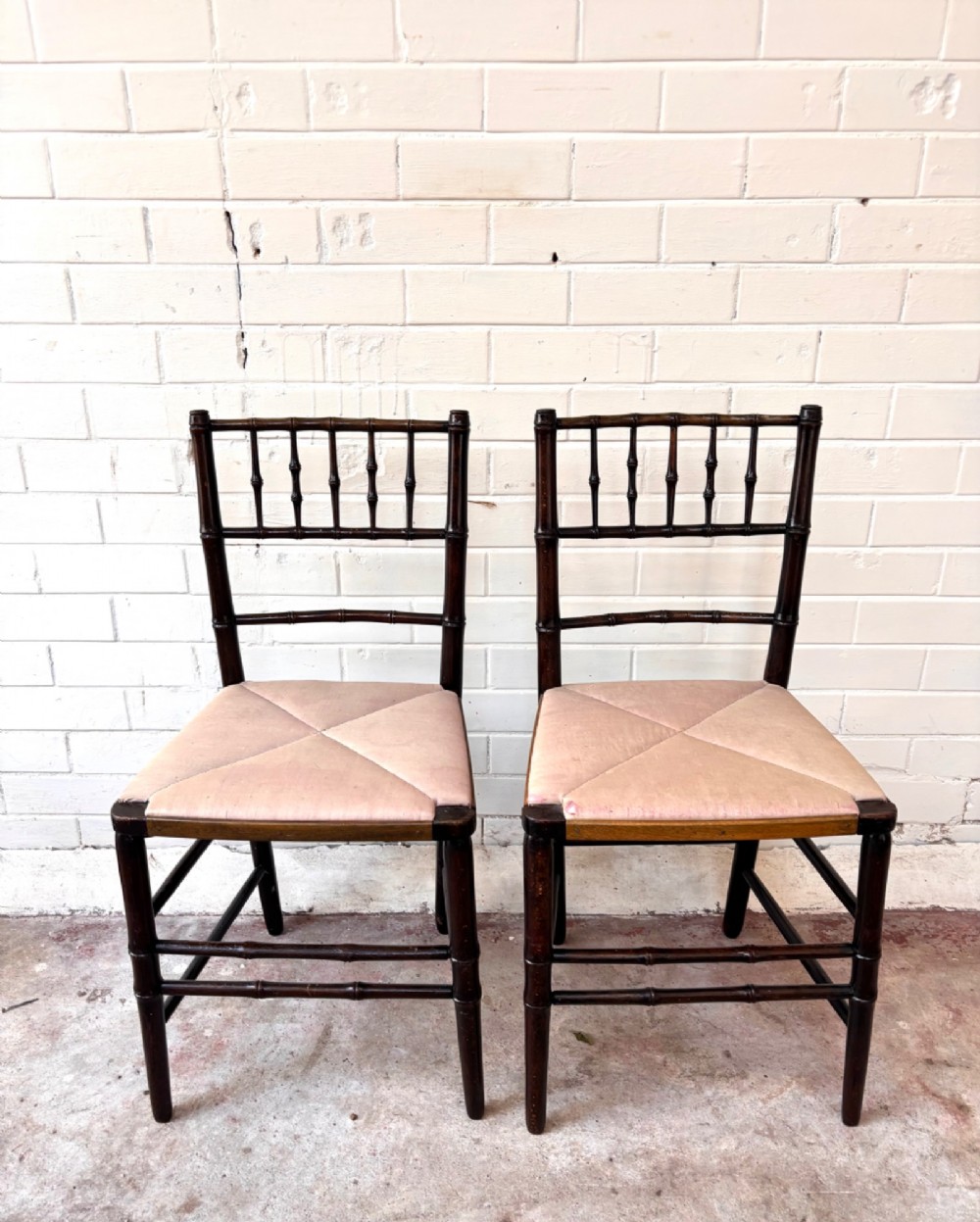 A pair of dark wood side chairs featuring turned frames imitating bamboo and light beige woven rush envelope seats. View II