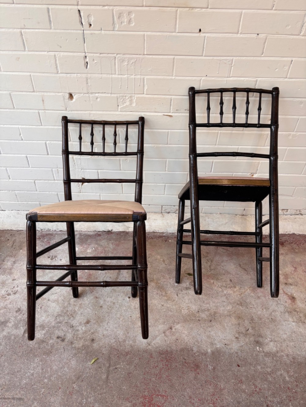 A pair of dark wood side chairs featuring turned frames imitating bamboo and light beige woven rush envelope seats. View IV