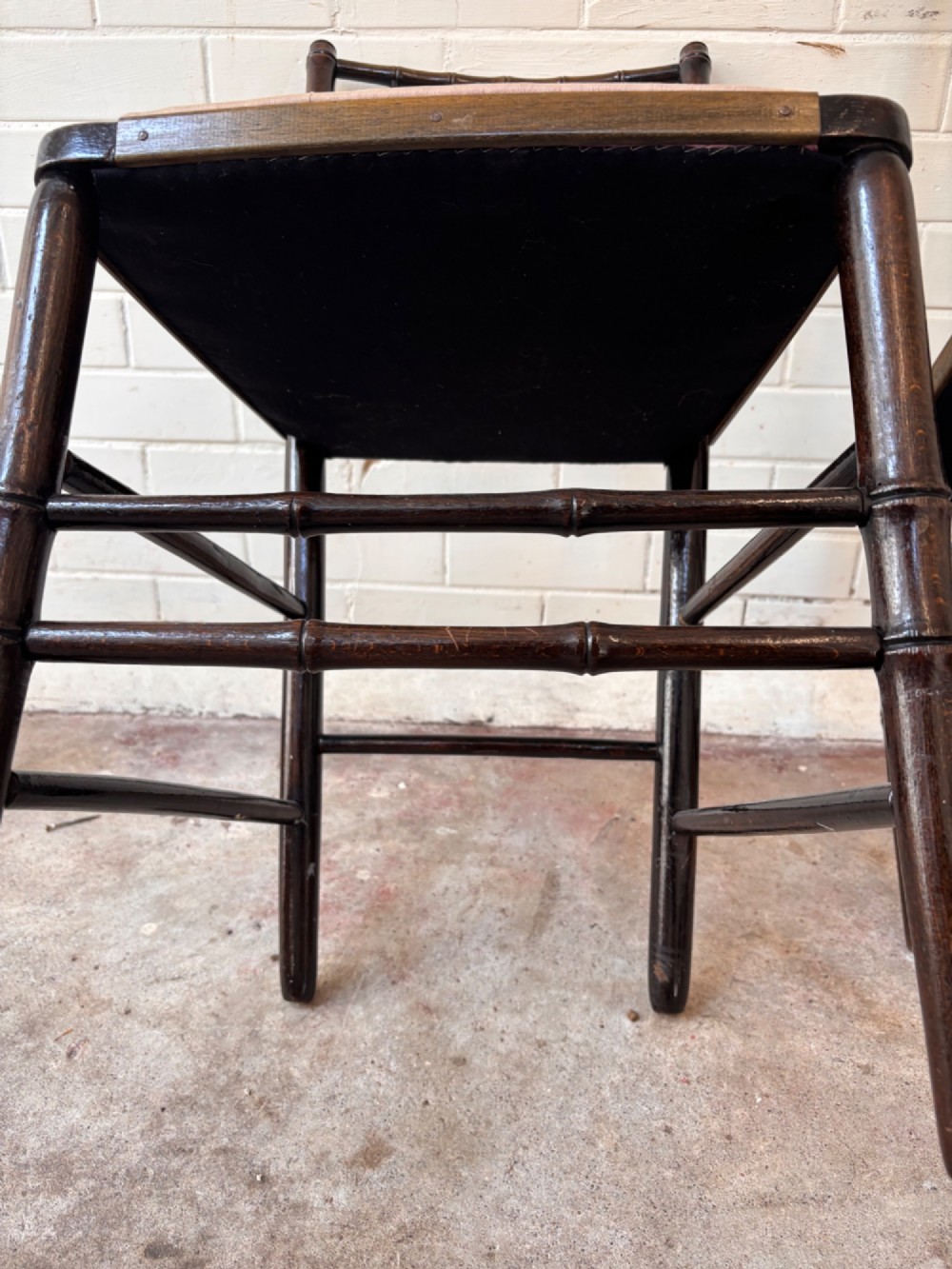 A pair of dark wood side chairs featuring turned frames imitating bamboo and light beige woven rush envelope seats. View V