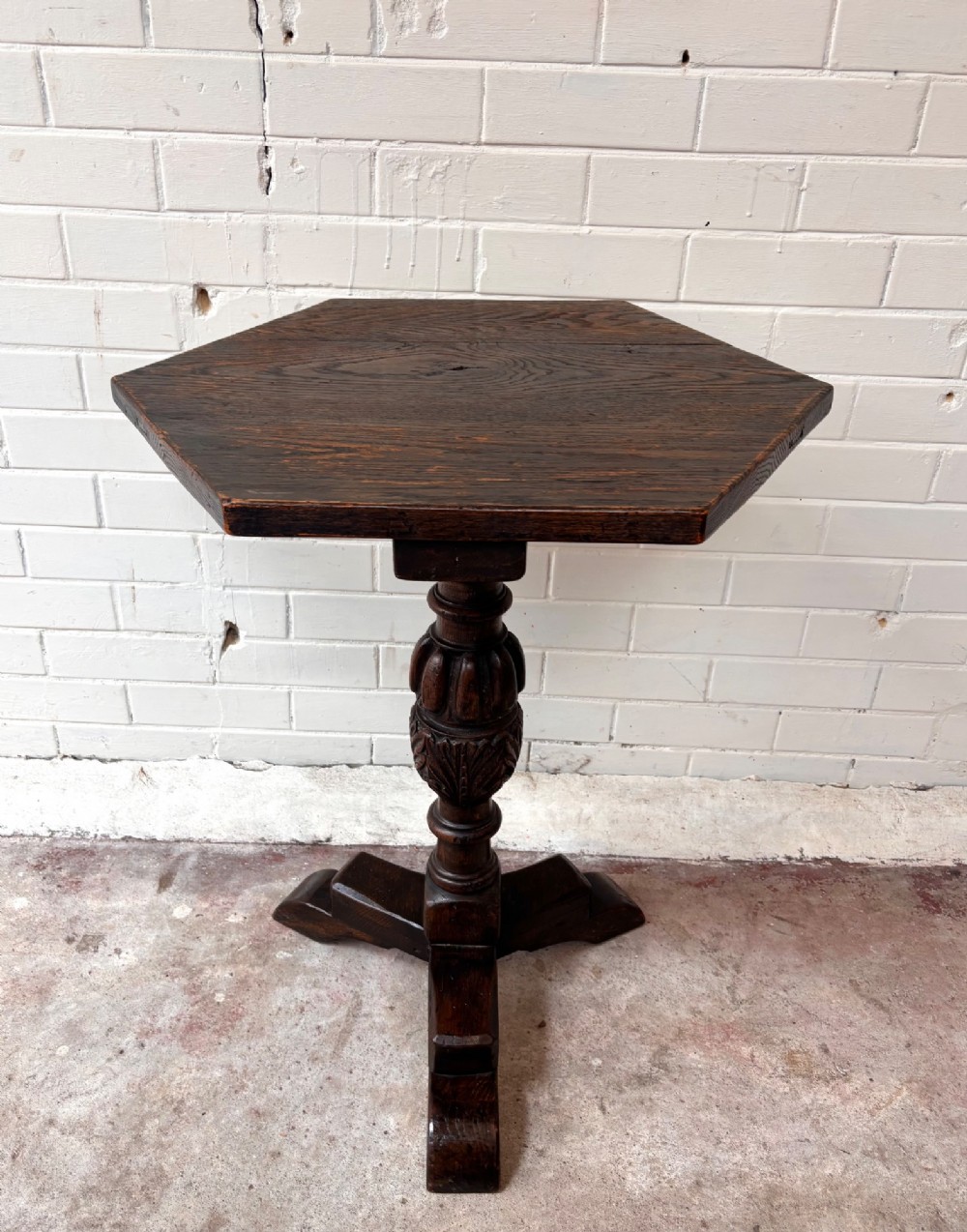 A dark oak pedestal side table featuring a hexagonal top resting on a carved central stem with tripod legs. View II