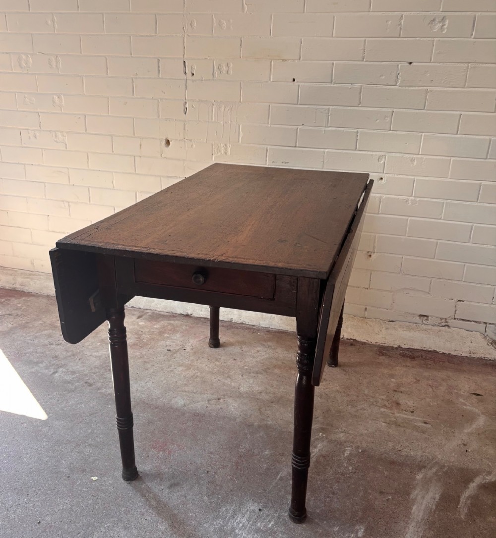 A dark brown wooden drop-leaf table featuring two hinged side leaves, a central drawer with a single knob, and slender turned legs. View IV