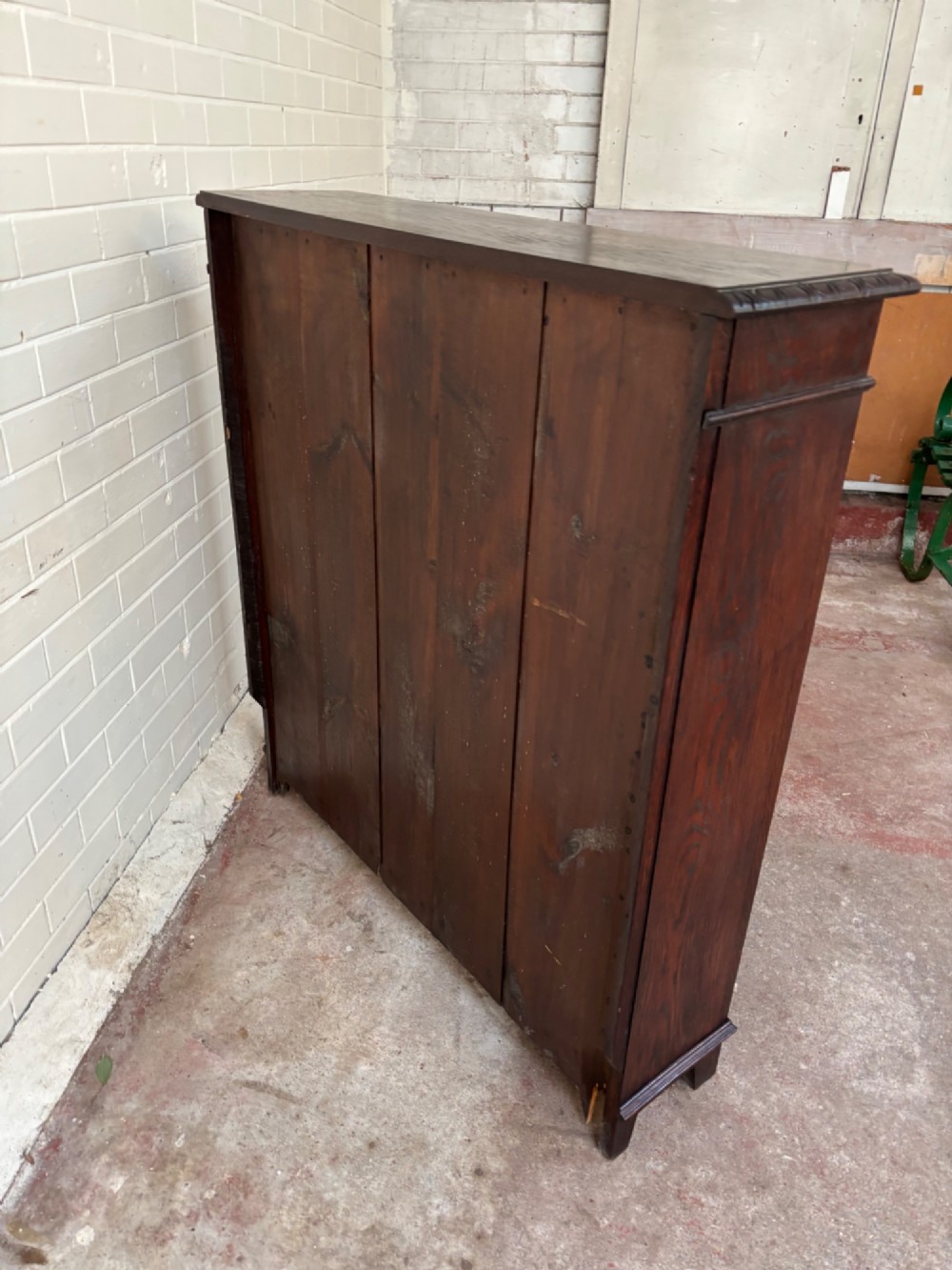 A low dark oak open bookcase featuring detailed lunette carving along the upper frieze and carved foliate borders down the upright sides. View VII
