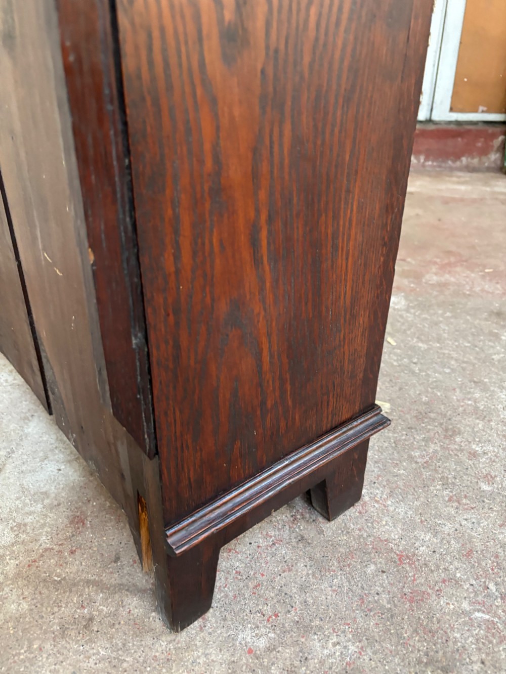 A low dark oak open bookcase featuring detailed lunette carving along the upper frieze and carved foliate borders down the upright sides. View VIII