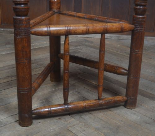 fig 1. A carved oak Turners armchair featuring a triangular seat, three lathe-turned legs, bobbin-turned armrests, and geometric chip carving on the crest rail.