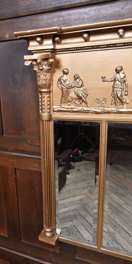 A Regency gilt overmantel mirror featuring a classical relief frieze above three bevelled mirror plates flanked by fluted Corinthian columns. View VII