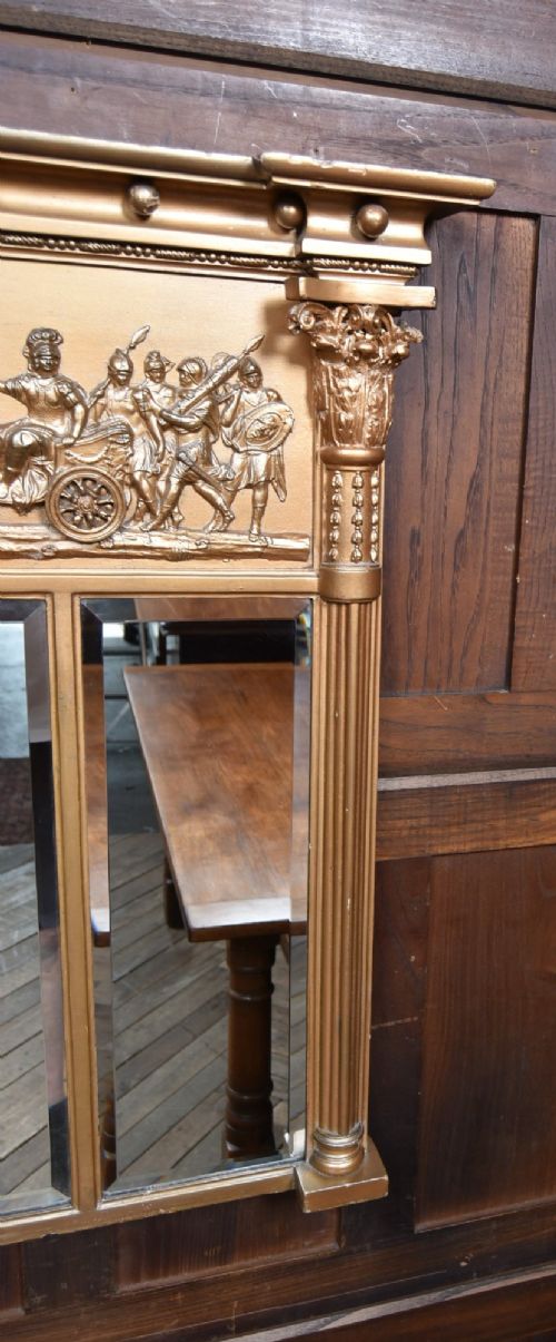 A Regency gilt overmantel mirror featuring a classical relief frieze above three bevelled mirror plates flanked by fluted Corinthian columns. View VIII