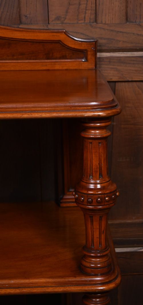 A Victorian mahogany three-tiered whatnot featuring turned column supports, two lower drawers with knob handles, an arched gallery top, and brass castors. View IV