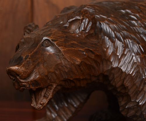 fig 1. A hand-carved dark wood bear sculpture featuring detailed gouged fur texture and an open mouth.