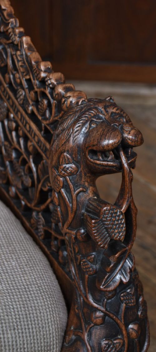 A nineteenth-century dark carved oak armchair featuring intricate openwork thistle motifs across the high arched back and sides, fitted with a floral needlepoint seat cushion. View III