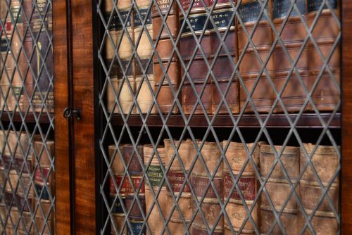 fig 1. An antique two-part Georgian mahogany bookcase featuring double upper doors with diamond brass wire grilles over lower flame mahogany cupboard doors.