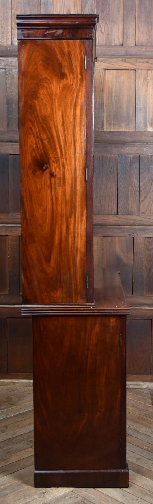 An antique two-part Georgian mahogany bookcase featuring double upper doors with diamond brass wire grilles over lower flame mahogany cupboard doors. View IX