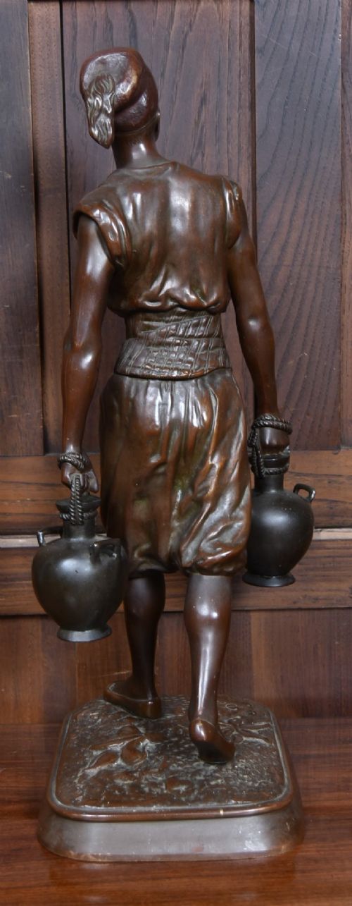 A dark brown patinated bronze sculpture depicting a standing Tunisian water bearer carrying two vessels on a rectangular moulded base. View VII