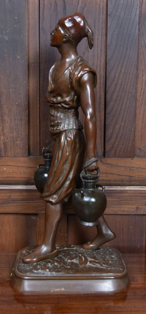A dark brown patinated bronze sculpture depicting a standing Tunisian water bearer carrying two vessels on a rectangular moulded base. View VIII