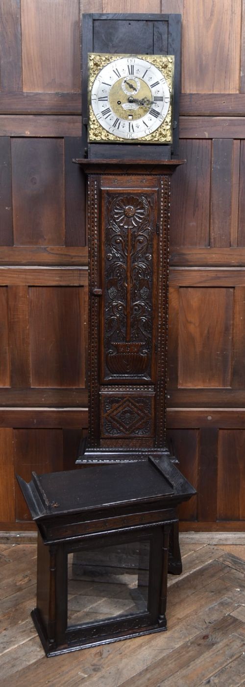 A tall carved dark oak longcase grandfather clock featuring intricate carved floral panels on the trunk and a brass dial signed John Smith Macclesfield. View VIII