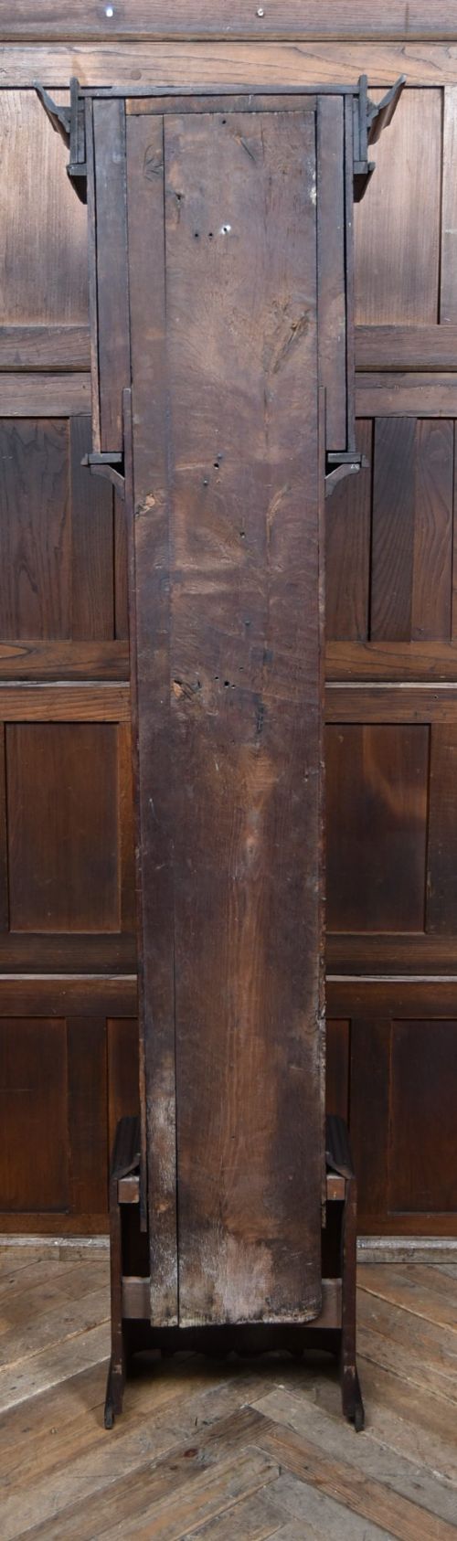 A tall carved dark oak longcase grandfather clock featuring intricate carved floral panels on the trunk and a brass dial signed John Smith Macclesfield. View X