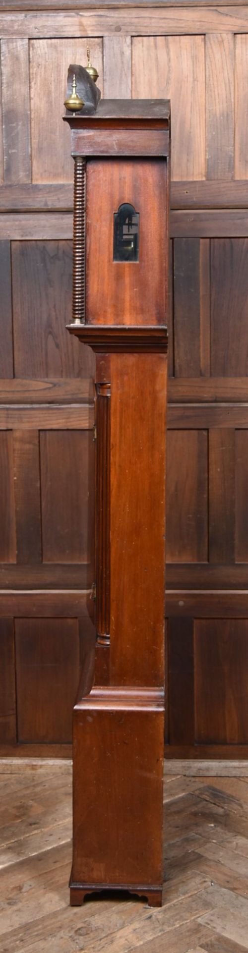 An antique Scottish flame mahogany longcase clock featuring a swan-neck pediment with brass finials and an arched painted dial. View XI