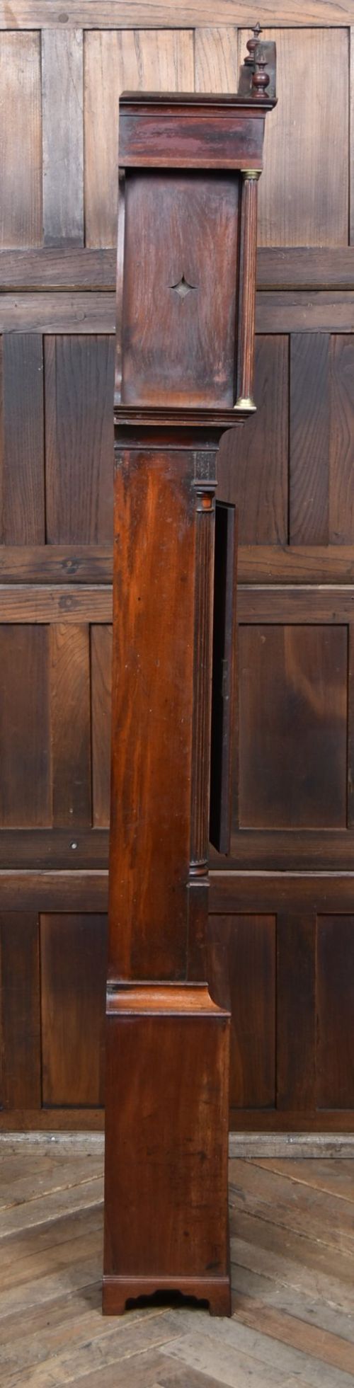 A Scottish mahogany longcase clock featuring a swan-neck pediment with brass finials, a hand-painted dial face, and flame mahogany veneers. View XI