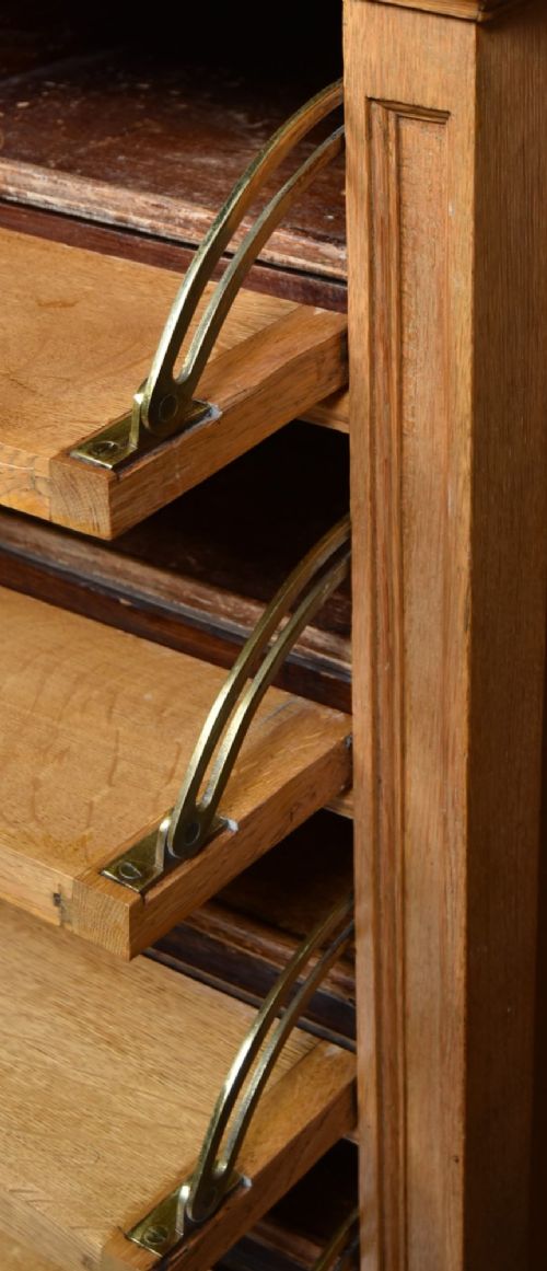 An Edwardian light oak filing cabinet with five stacked fall-front drawers featuring brass ring pulls, supported on square legs with a lower open shelf. View XI
