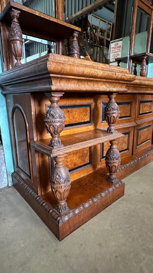 A large Victorian pollard oak mirror-back sideboard featuring carved urn finials, central mirror glass, open side shelving, and ebonised drawer borders. View VI