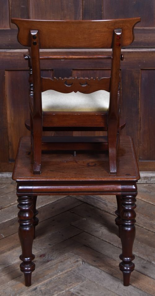 A Victorian metamorphic mahogany childs high chair with turned legs, curved armrests, a carved backrest crest, and cream fabric upholstery. View VI