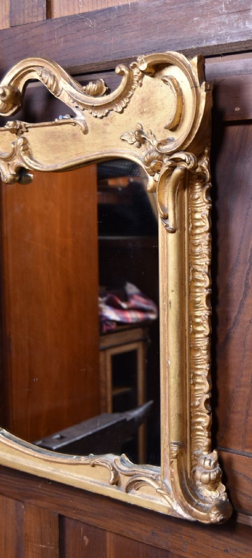 A wide Rococo style horizontal overmantel mirror with an ornate carved giltwood frame featuring an asymmetrical crest and C-scroll motifs. View VIII
