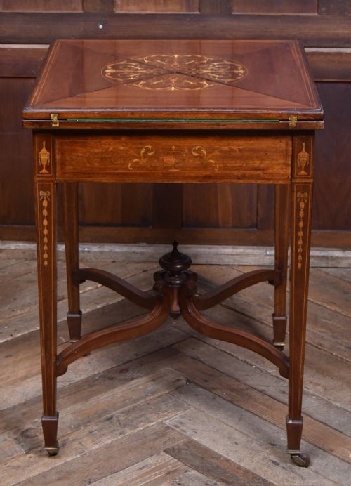An Edwardian mahogany envelope card table featuring satinwood marquetry inlay, a single drawer, and a curved cross-stretcher with brass castors. View XIII