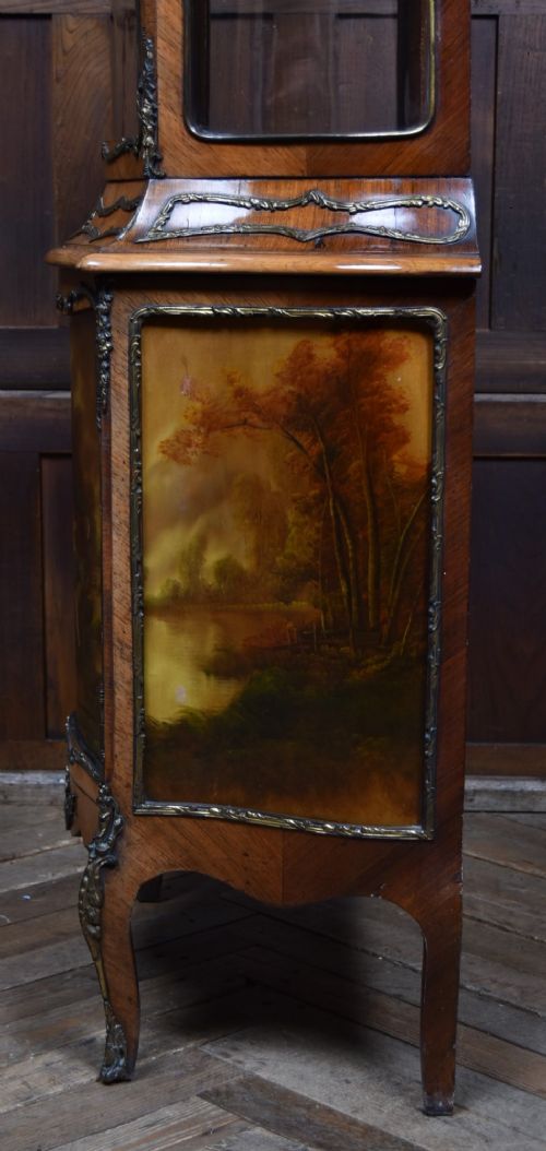 A French walnut vitrine cabinet featuring curved glass upper panels, gilt-bronze ormolu mounts, cabriole legs, and a hand-painted lower door panel depicting a figurative scene. View XV