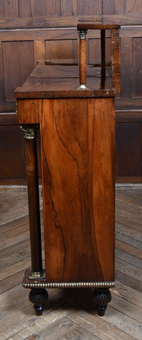 A Victorian dark rosewood chiffonier cabinet featuring a decorative brass inlay border, brass mask accents, two pleated silk fabric door panels, turned feet, and a raised upper tier shelf. View XIII
