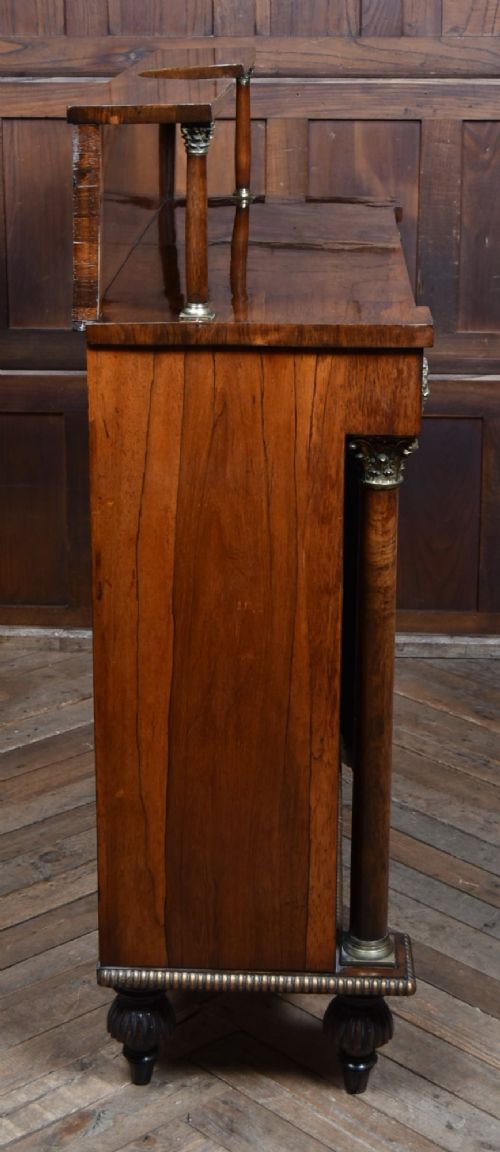 A Victorian dark rosewood chiffonier cabinet featuring a decorative brass inlay border, brass mask accents, two pleated silk fabric door panels, turned feet, and a raised upper tier shelf. View XIV