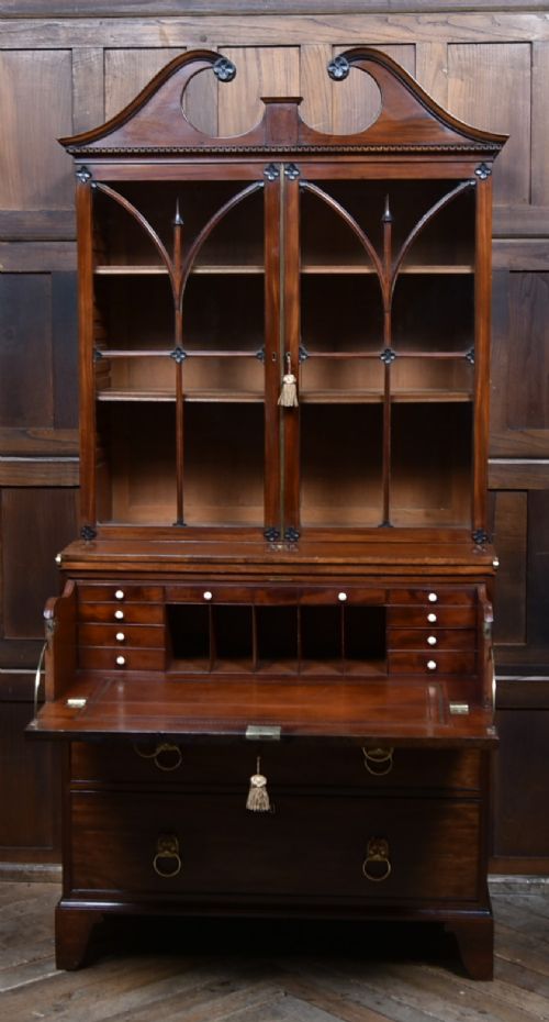 An early nineteenth-century mahogany secretaire bookcase featuring a swan-neck pediment, astragal glazed upper doors, and a lower chest of drawers with brass lion-head handles. View II