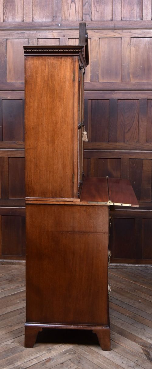 An early nineteenth-century mahogany secretaire bookcase featuring a swan-neck pediment, astragal glazed upper doors, and a lower chest of drawers with brass lion-head handles. View X